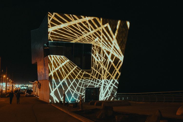 Lighting display with intersecting lines of gold on the side of a building